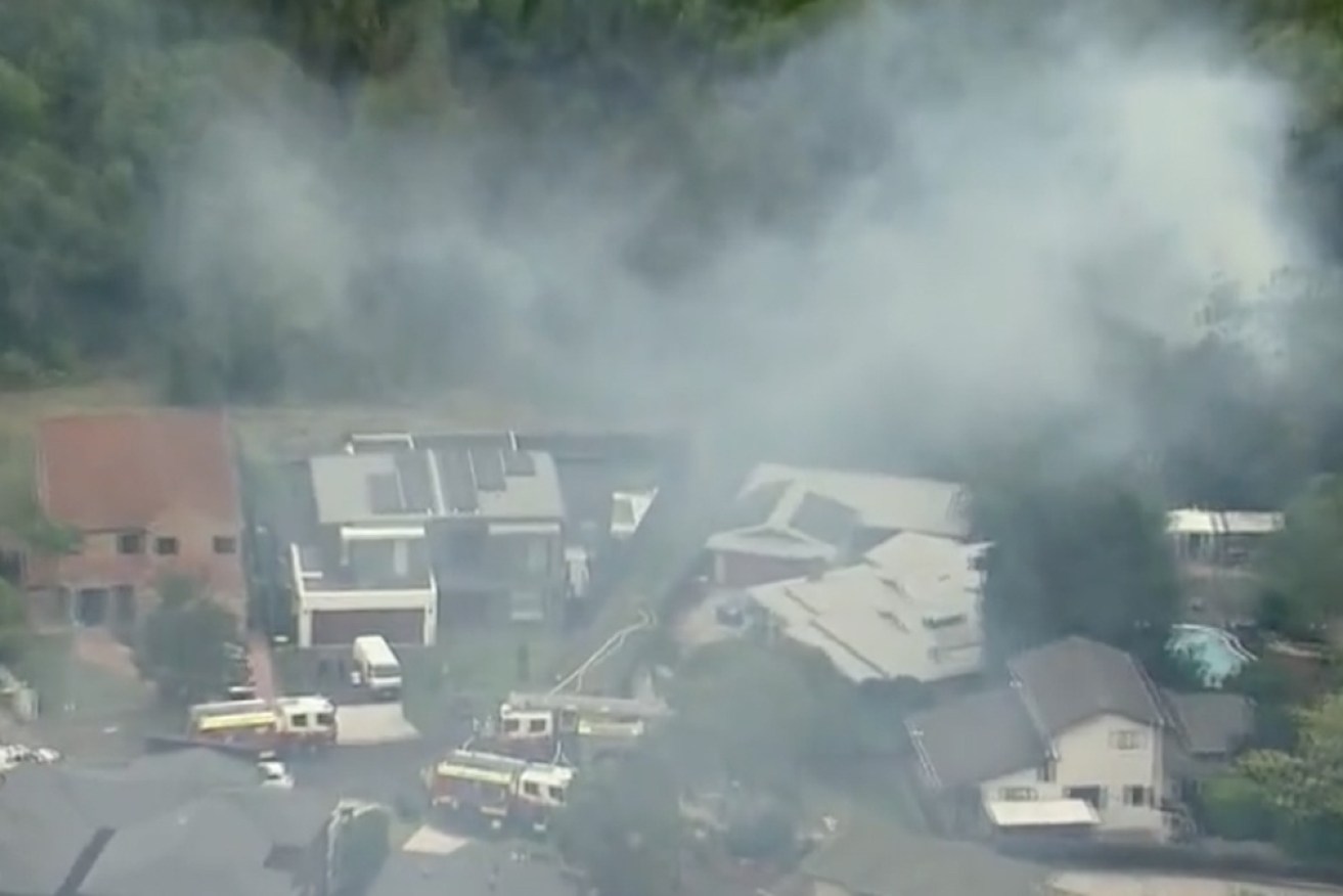 The fire was burning in bush behind houses in Revesby Heights on Thursday afternoon.