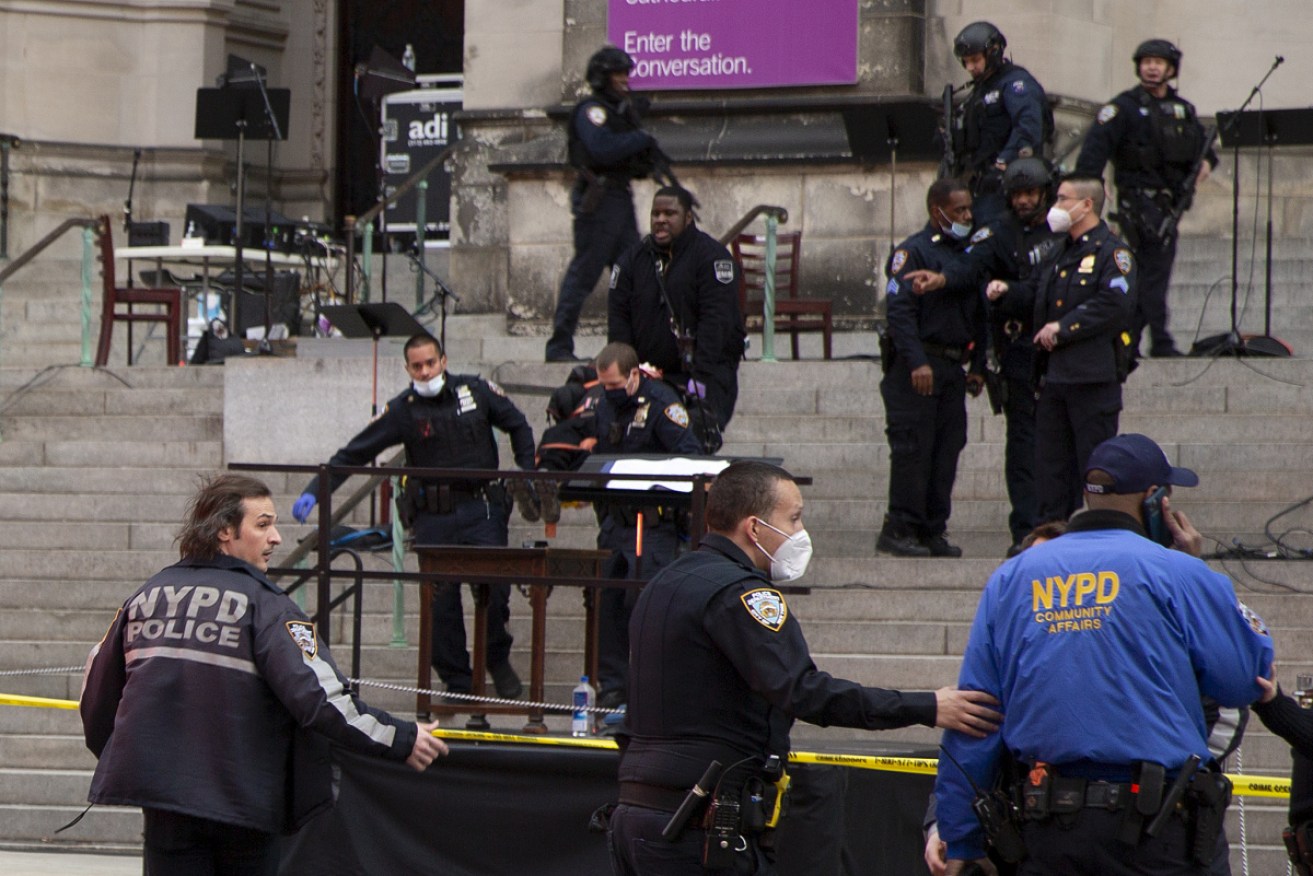 New York police officers carry a suspected gunman in a stretcher down the steps of Cathedral Church of St John the Divine.