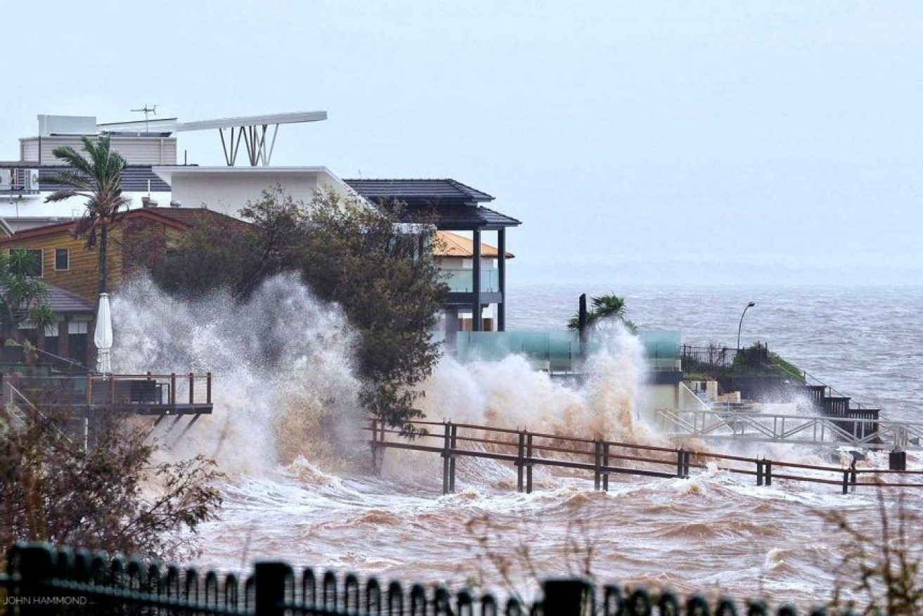 Waterfront homes at Scarborough in the Moreton Bay region are lashed by wild weather and big swells.