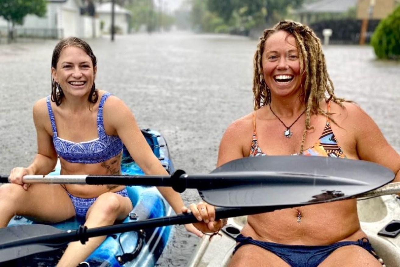 Two women go kayaking in floodwaters at Riverside Drive in Currumbin.