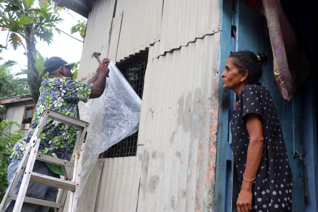 A resident secures his house by placing plastic sheets on the windows ahead of the arrival of super Cyclone Yasa in Fiji's capital city of Suva.  