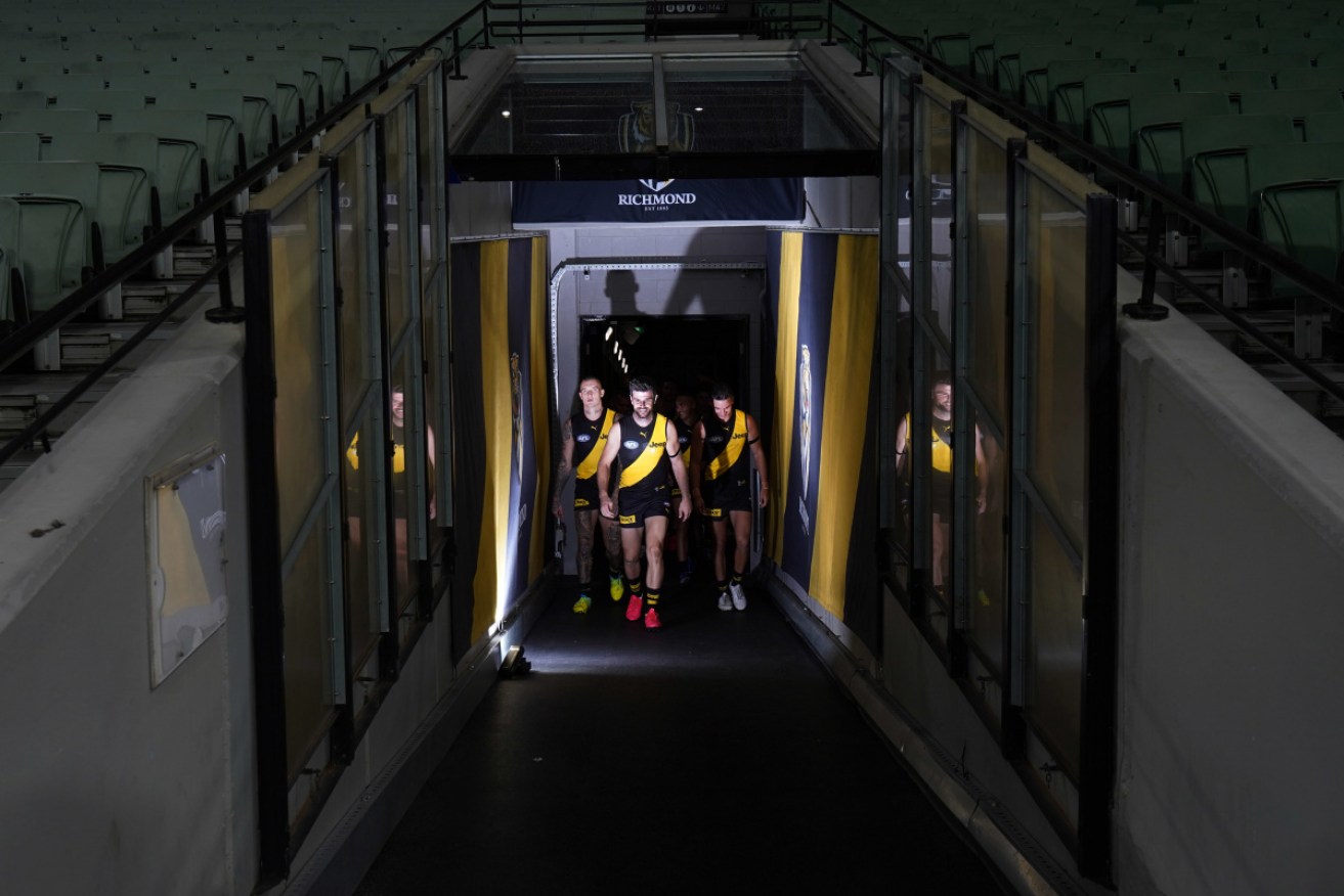 Richmond walk onto the field for their first game of 2020 against Carlton at an empty MCG.