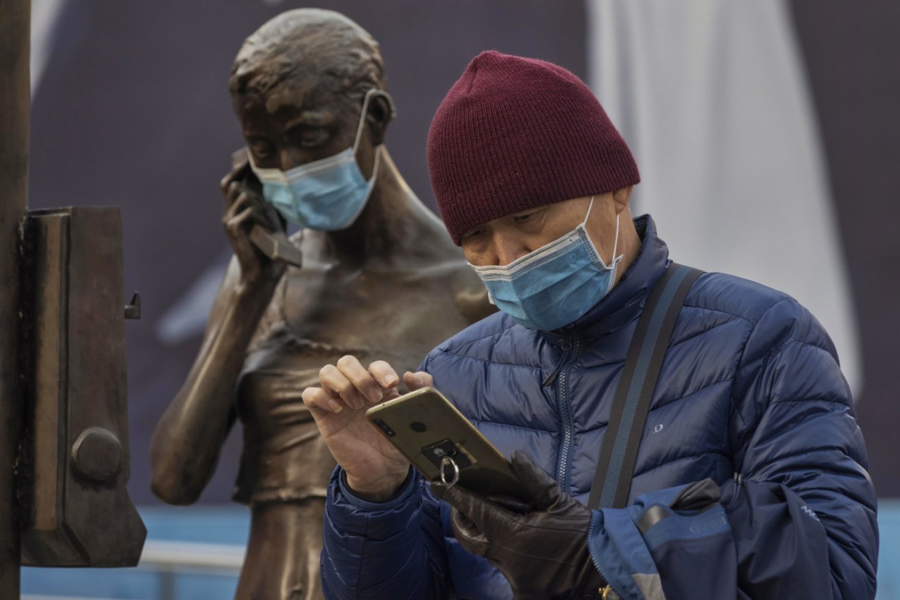 A man checks his phone in Shanghai as Shijiazhuang and Xingtai are locked down after a spike in COVID-19 cases.