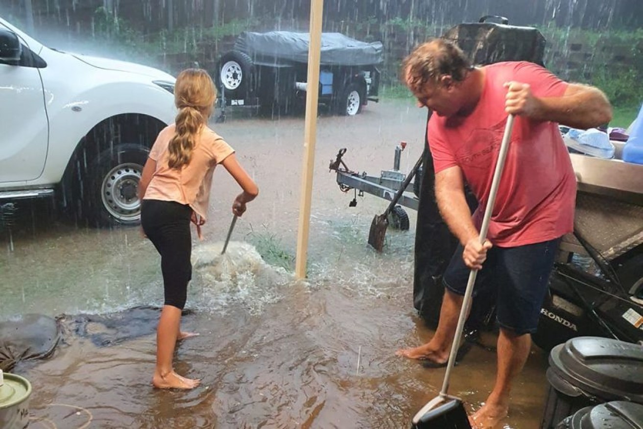 An Alexandra Hill family tries to stop floodwater entering their home.