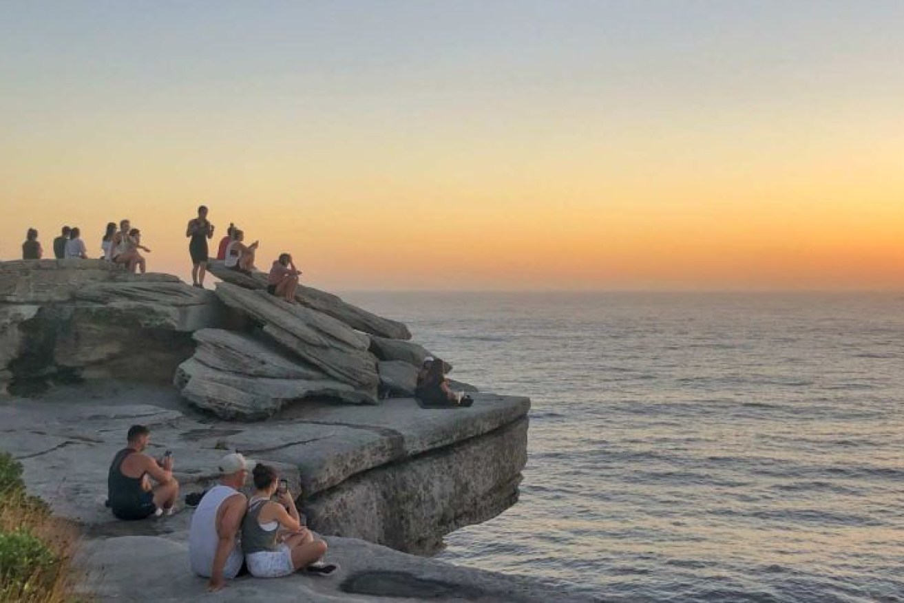 People gather at Bondi to watch the sunrise looking out over the Tasman Sea. 
