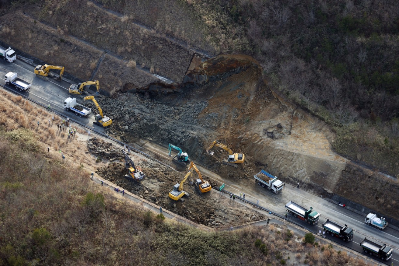 Excavators remove debris following a landslide covering Joban Expressway in the aftermath of the quake in Soma, Fukushima prefecture.
