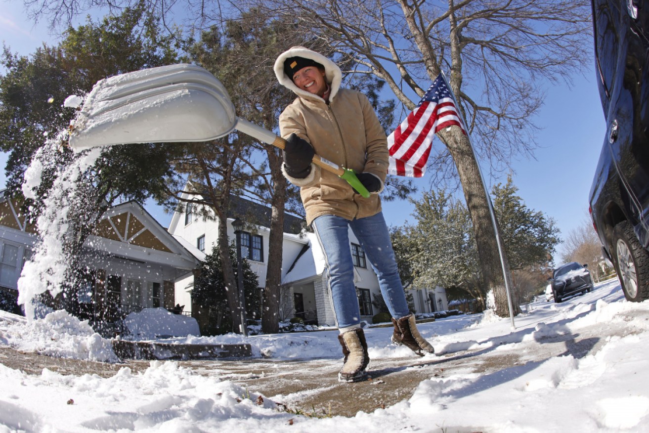 Honey Russell shuffles snow from the front of her property in Fort Worth, Texas.