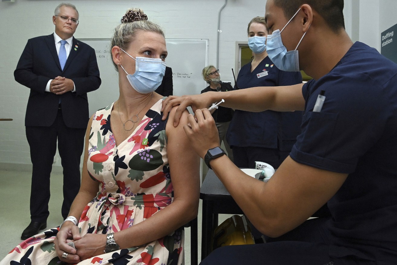 Scott Morrison watches as Sarah Fletcher is taken through the procedure of receiving a vaccine at the Sydney local health district vaccination hub in Sydney. 