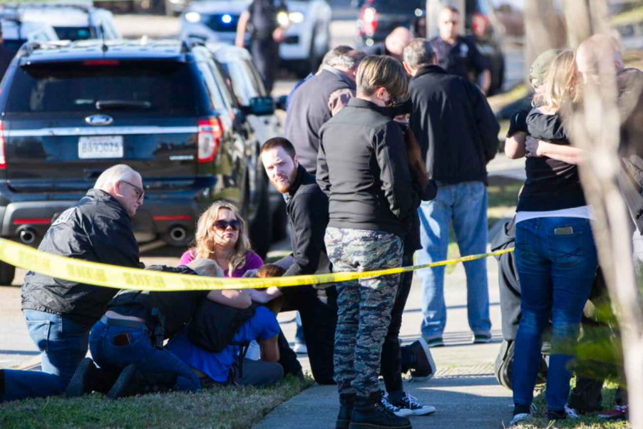 Stunned survivors find comfort in each other's arms outside the New Orleans gun mart.