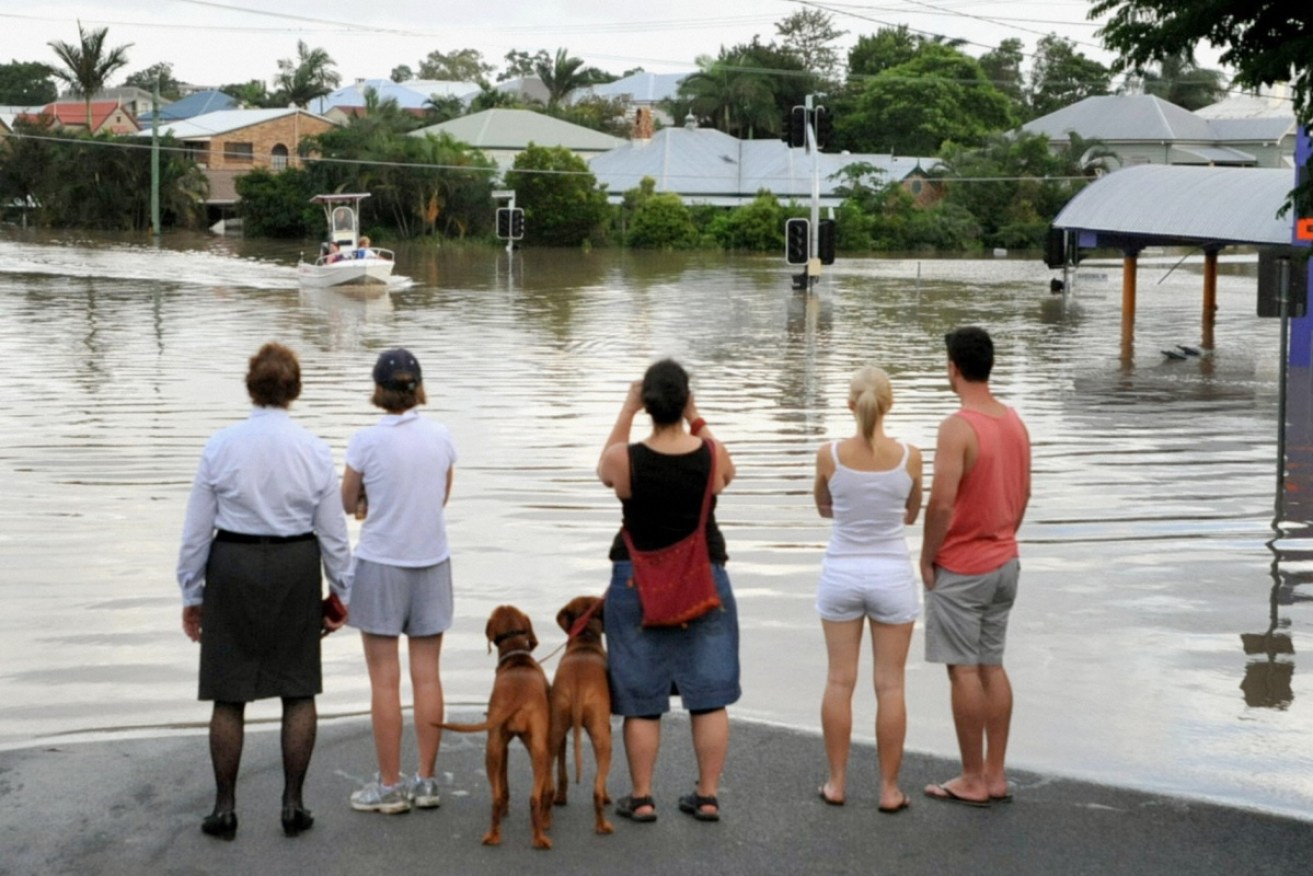 Residents watch a boat on a flooded Brisbane street in 2011.