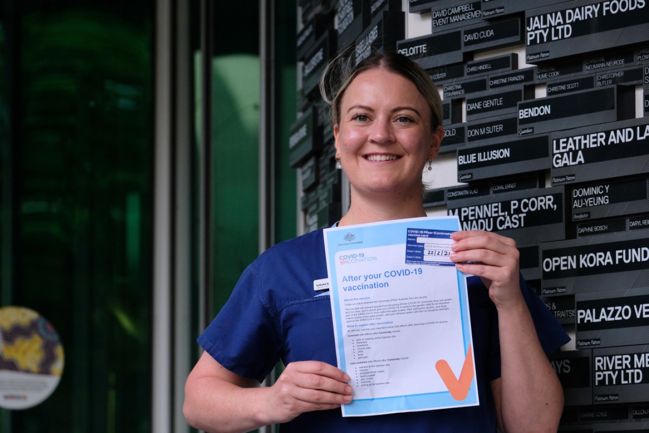 Melbourne nurse manager Grace Gibney shows off her vaccine certificate.