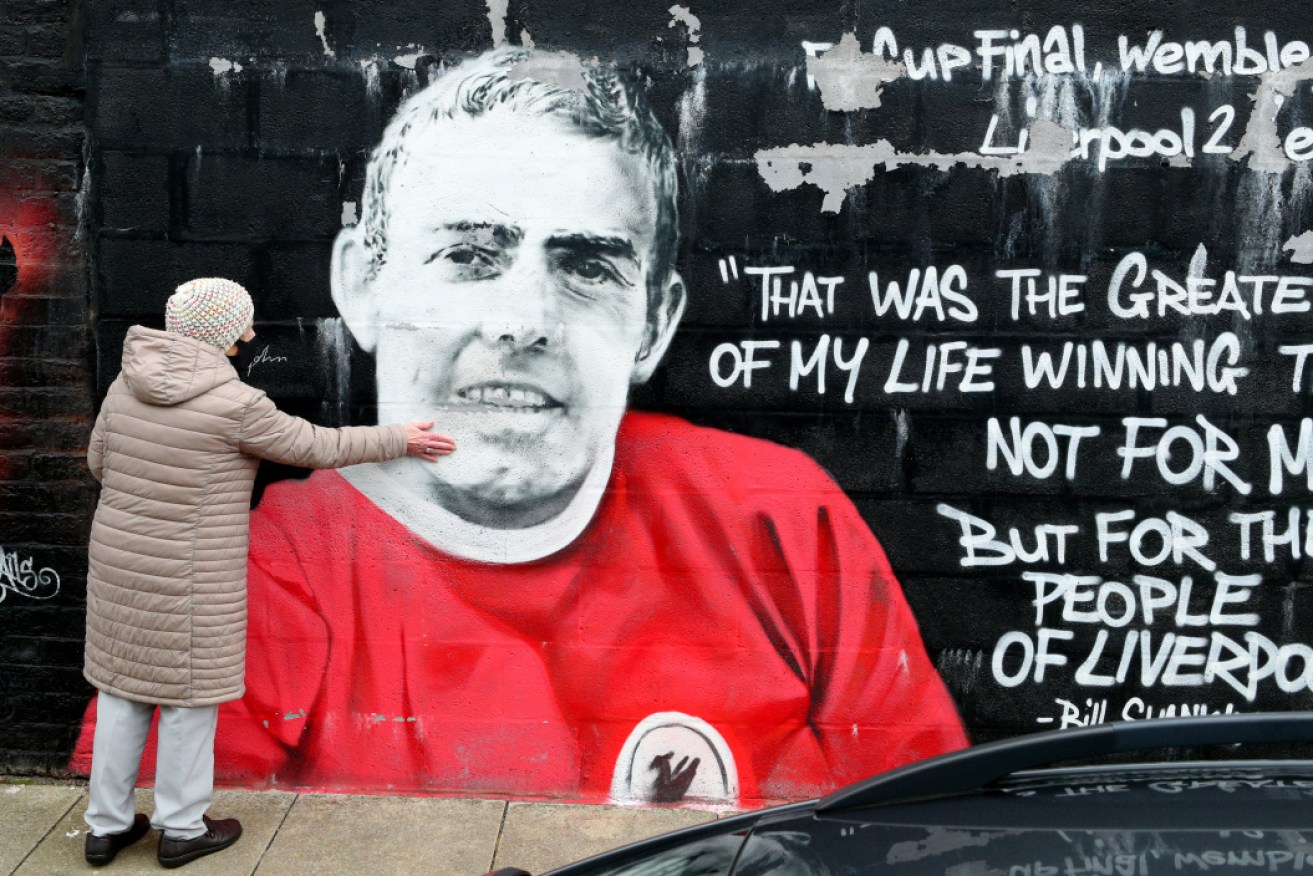 A woman touches the Murwalls mural of Ian Saint John, who has died at the age of 82.