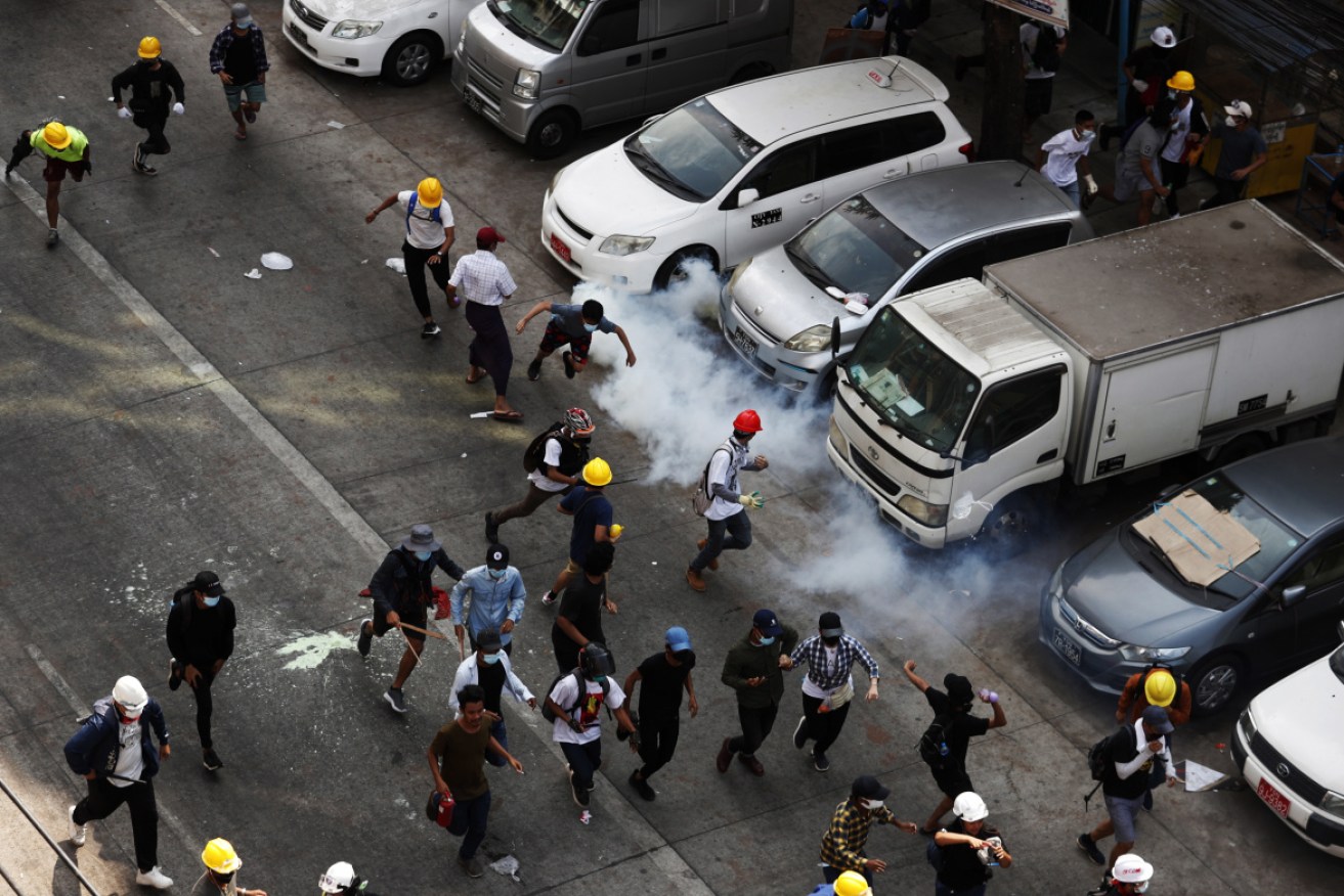 Demonstrators react as tear gas is fired by police during a protest against the military coup in Yangon.