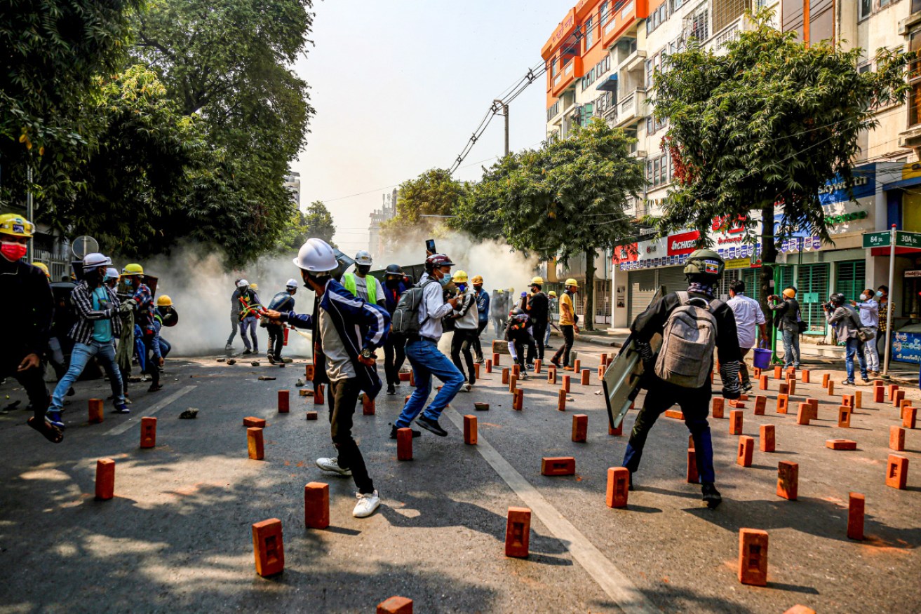 Anti military coup protesters run after police thrown tear gas canisters during a demonstration against the military coup.