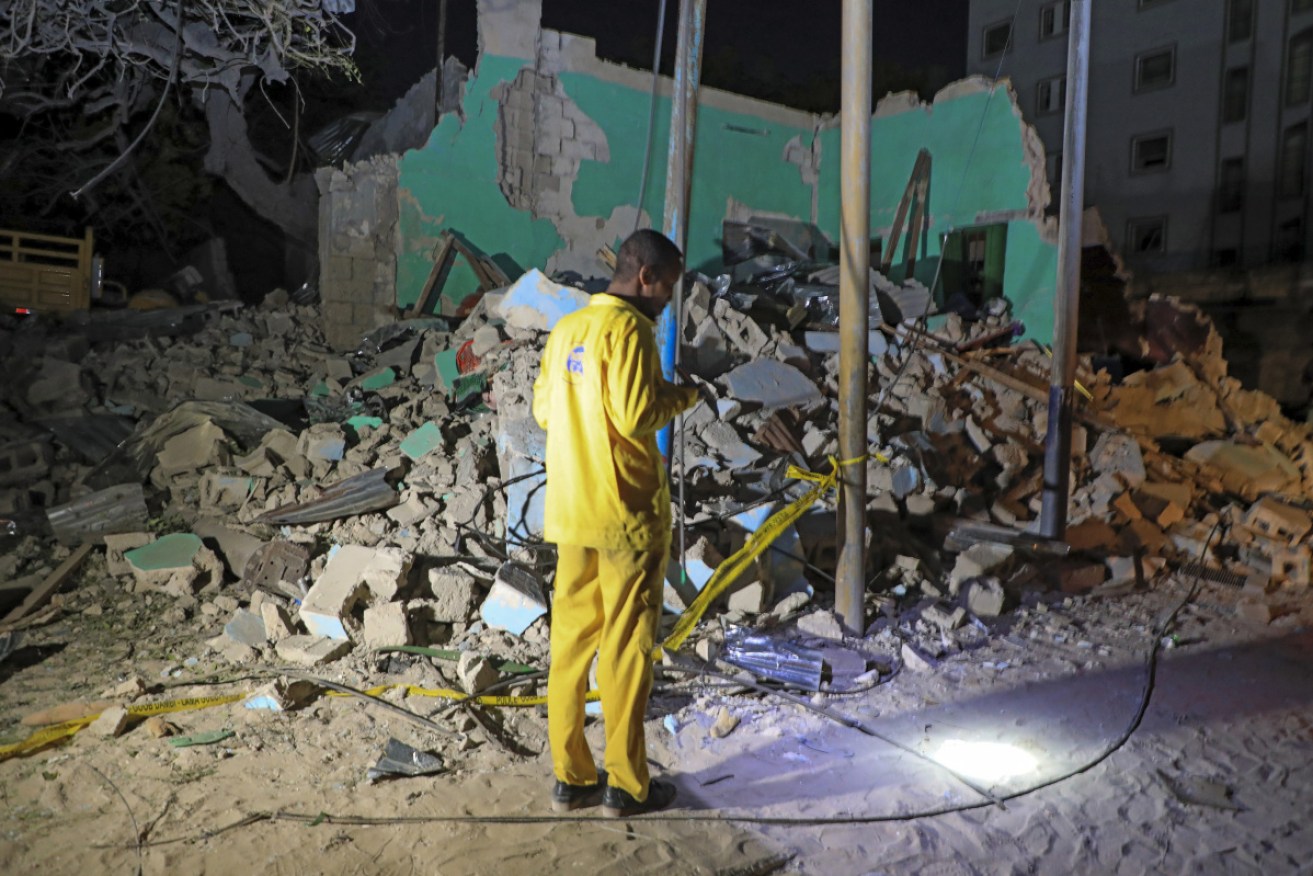 A man observes a destroyed building at the scene of the blast at a popular restaurant in Mogadishu, Somalia. 