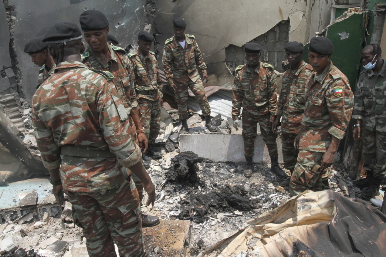 Military personnel view debris in the aftermath of an explosion.