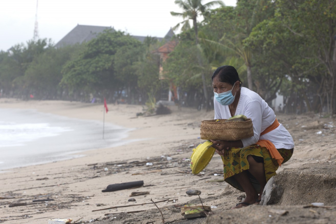 A Balinese woman gives an offering to Hindu god on a beach in early February.