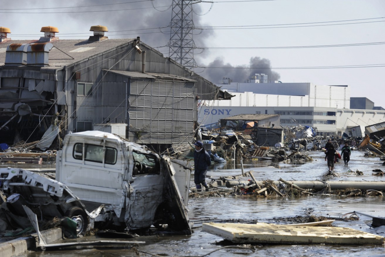 Survivors walk among the devastation left by the tsunami on March 11, 2011.