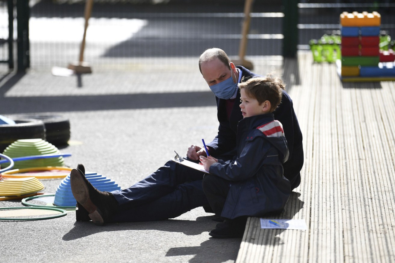 Prince William talks with a child in the playground during a visit to a school in east London.