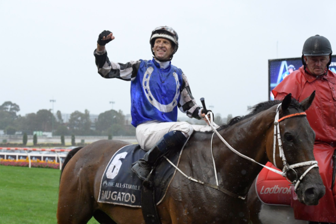 Champion jockey Hugh Bowman raises a winner's fist after piloting Mugatoo to victory in the world's richest one-mile turf race.