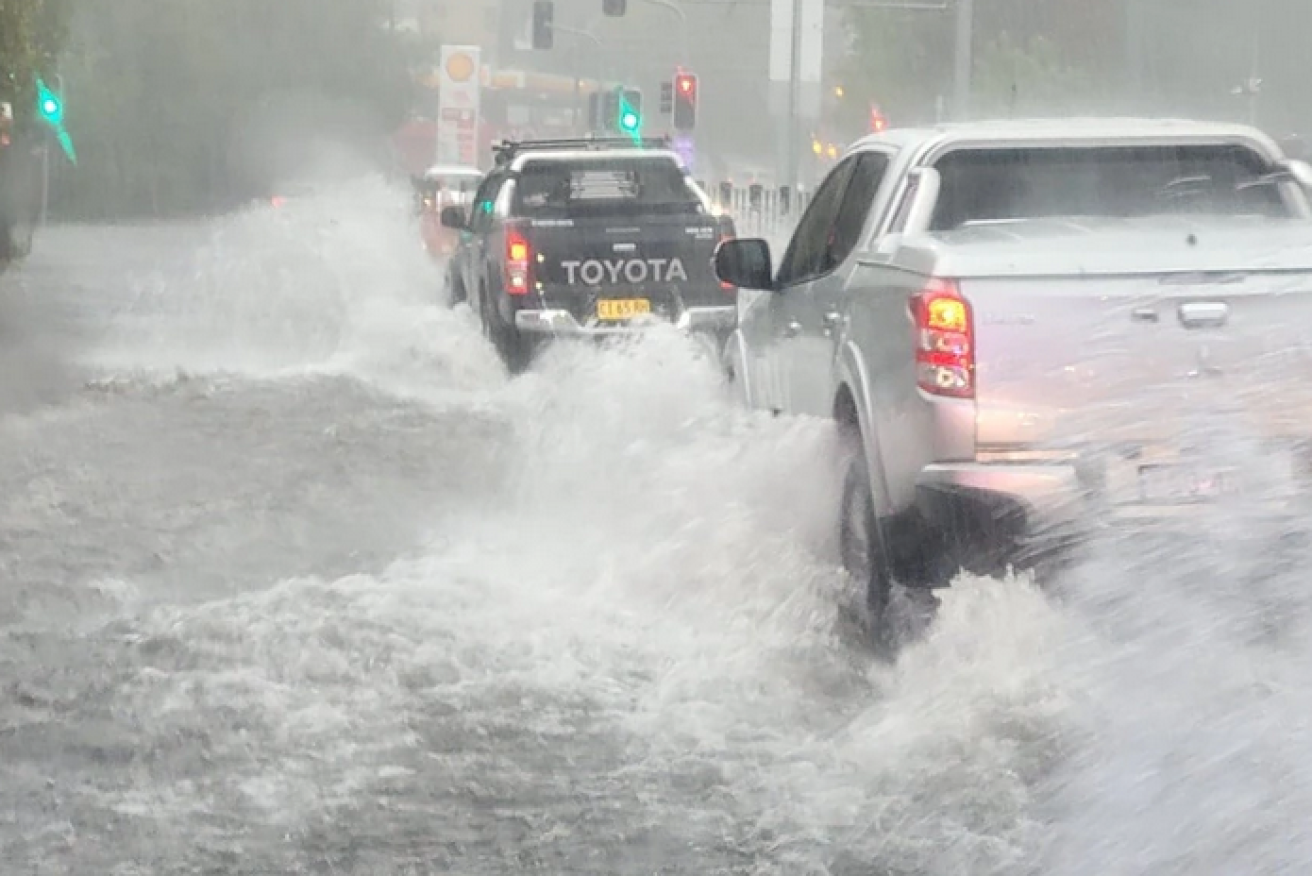 Despite official warnings to stay off the roads, these drivers plough through a flooded street in Randwick.