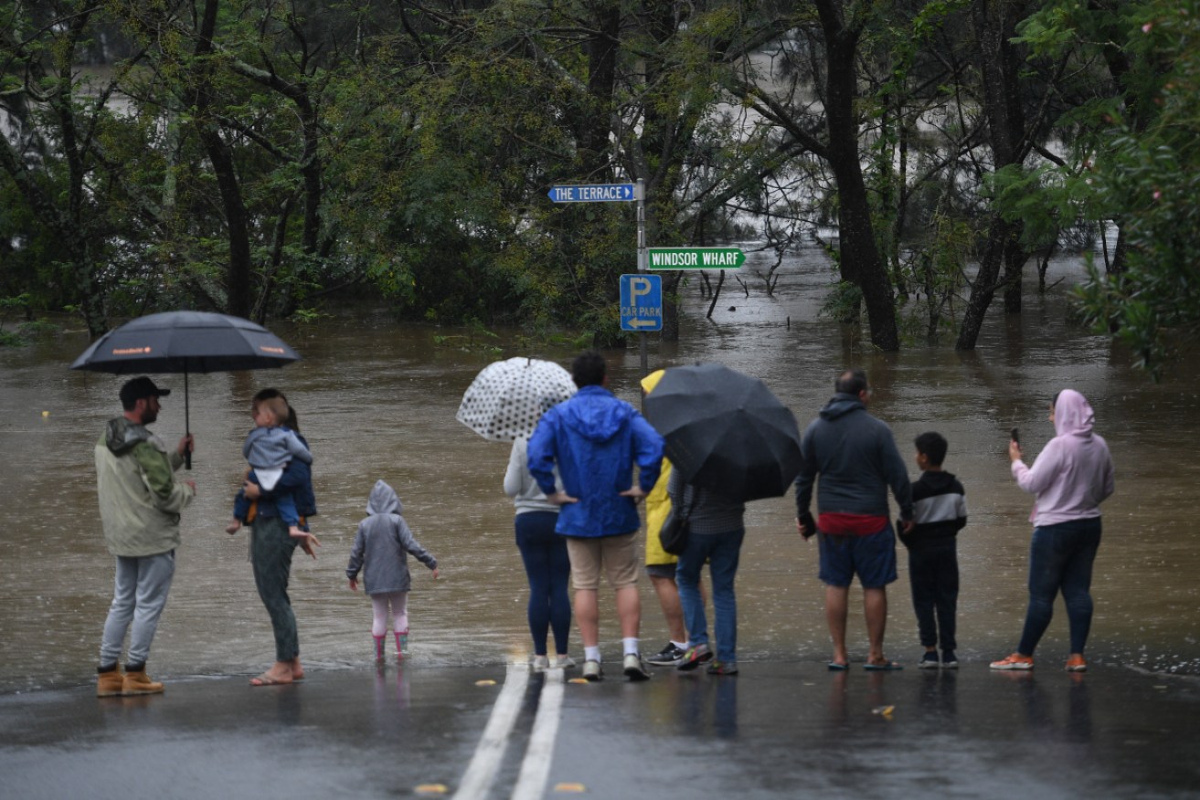Onlookers watch the submerged New Windsor Bridge in the north west of Sydney on Monday.