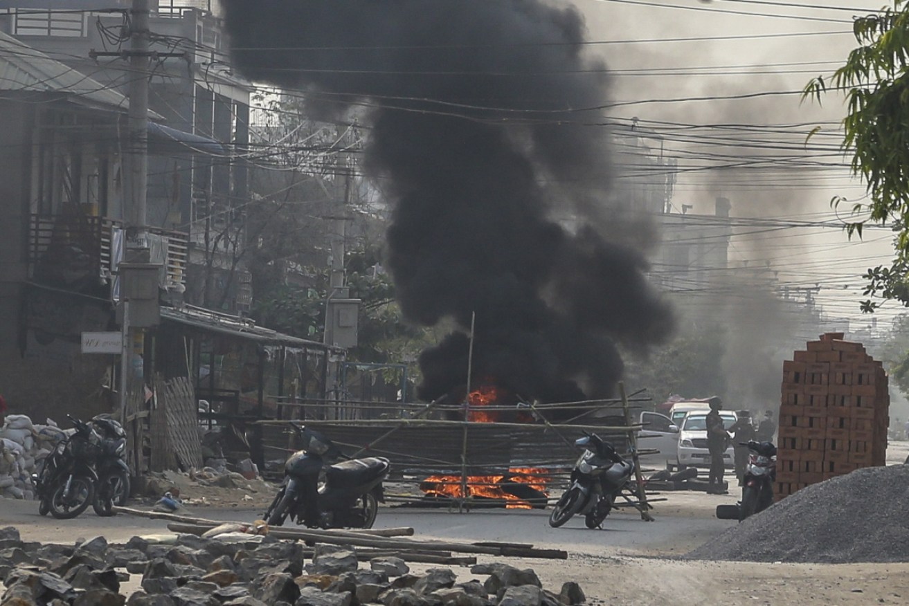 Security forces stand next to a burning police motorcycle burned by demonstrators.