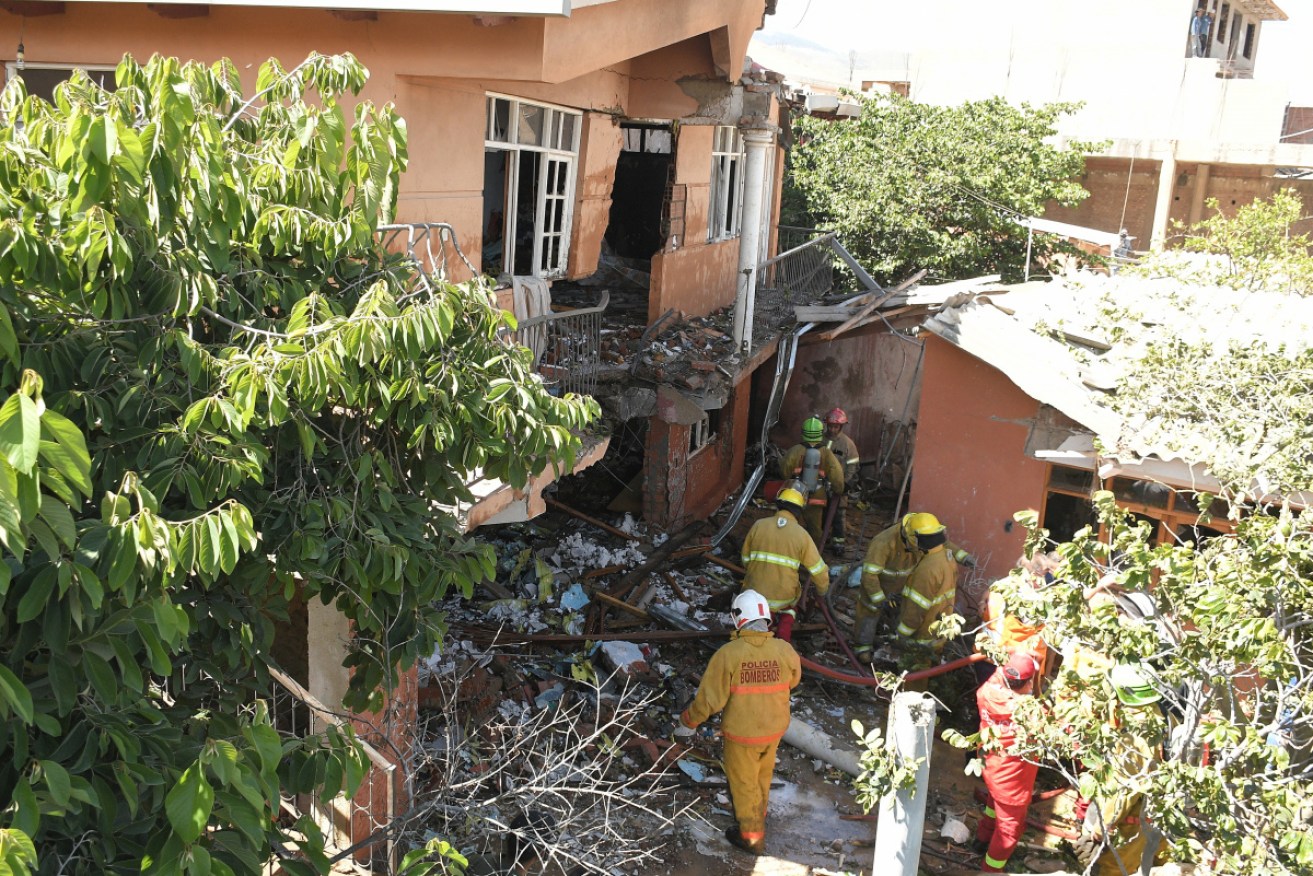 Firefighters inspect the damaged house where the plane crashed and the woman died.