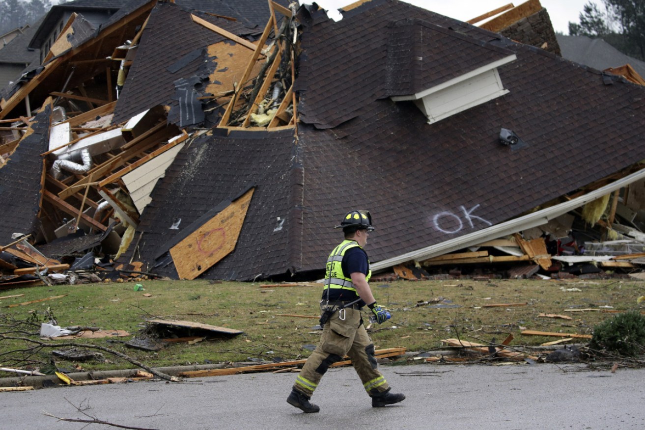 A firefighter surveys damage to a house after a tornado touches down south of Birmingham, Alabama.