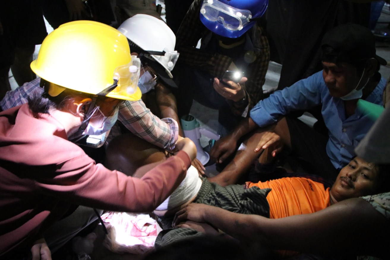 Anti-coup protesters attend to a man with a bandage on his right leg in the Dala township of Yangon, Myanmar.