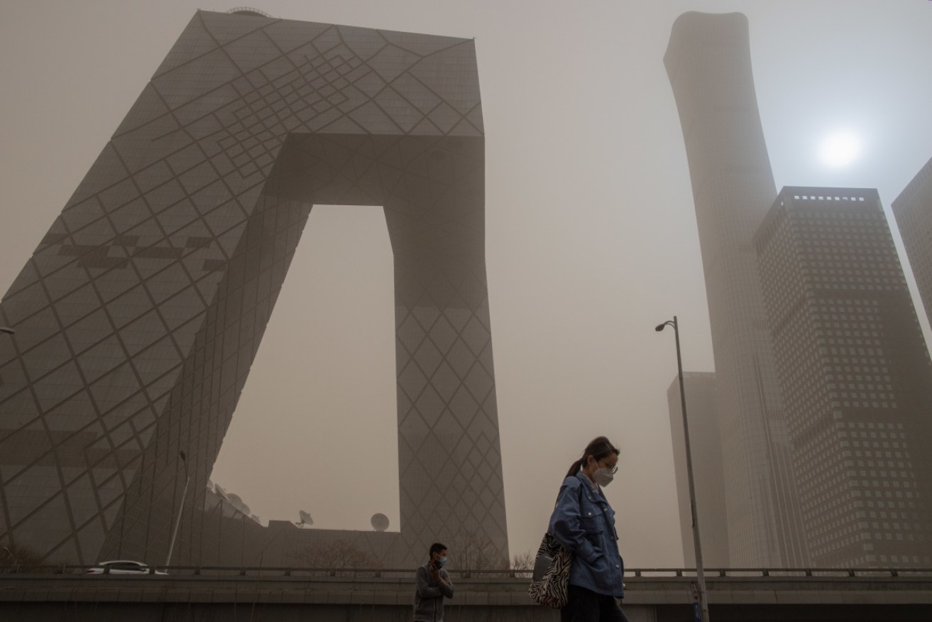 People wear face masks walk as a sandstorm hits Beijing's CBD on Sunday.