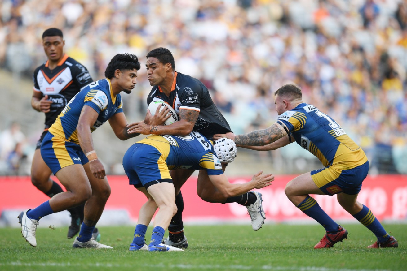 Wests Tigers’ Joe Ofahengaue is tackled by Parramatta’s Reed Mahoney at Stadium Australia in Sydney on Monday.