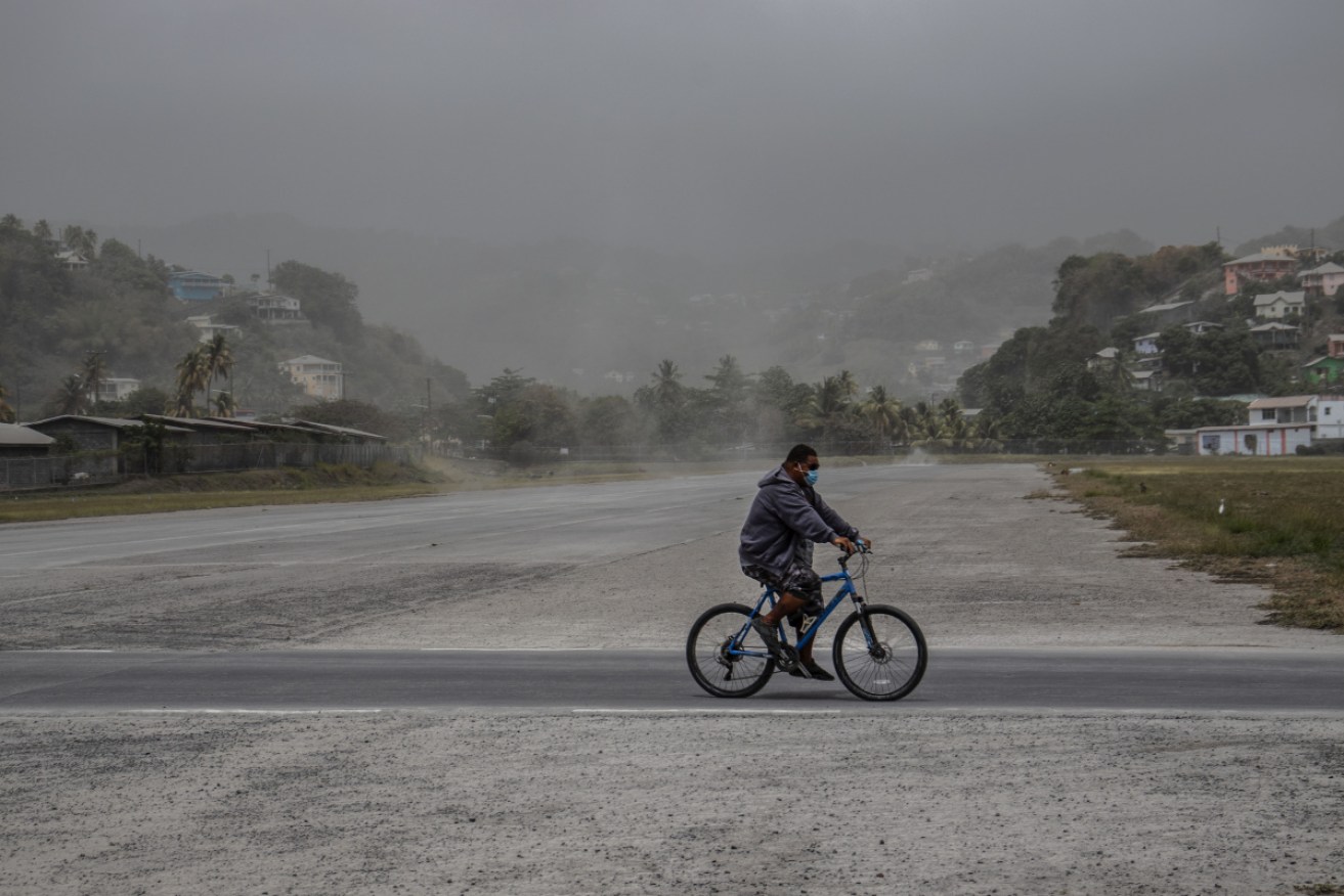 A man rides his bicycle past fields covered with volcanic ash a day after the La Soufriere volcano erupted.