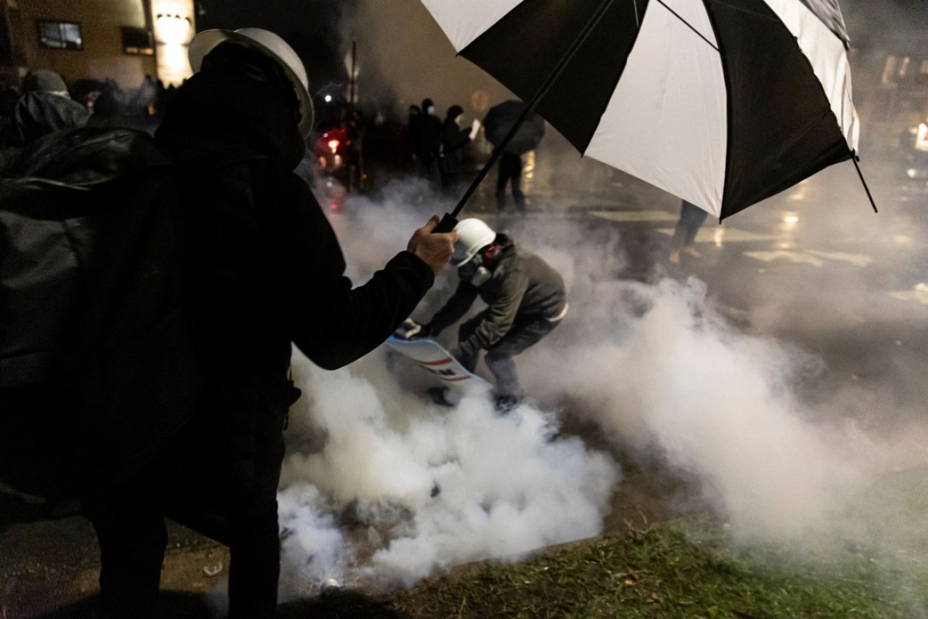 People run for cover after police fired tear gas at protesters outside the Brooklyn Centre.