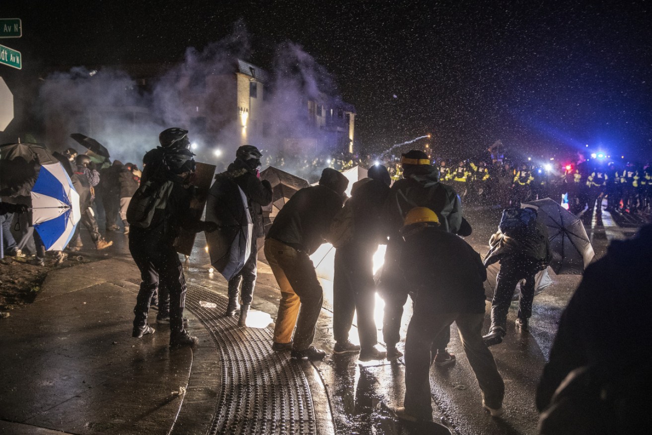 Protesters are illuminated by a flash bang grenade during a clash with law enforcement officers near the Brooklyn Centre Police Department.