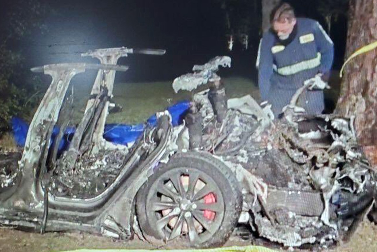 The burned out remains of the vehicle are inspected.