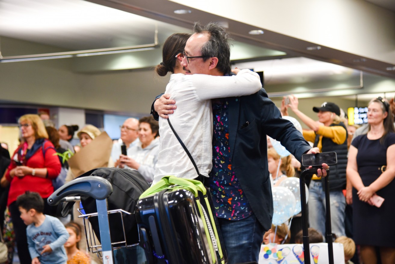 Families and loved ones embrace after landing in Wellington on the first day of the trans-Tasman bubble.