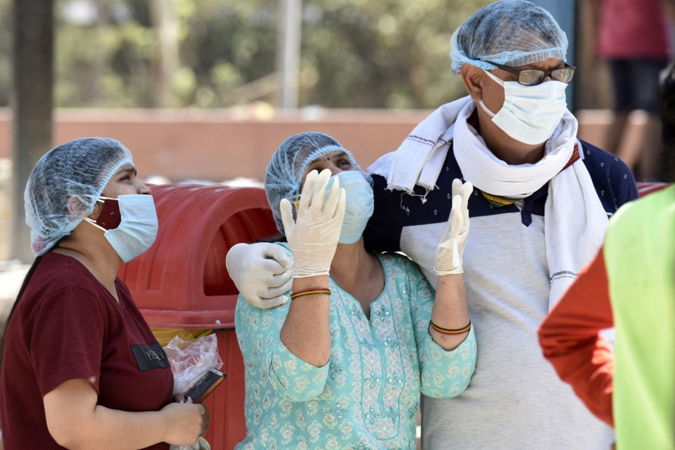 Relatives of a person who died of Covid-19 at a crematorium in Noida, India. Photo: Getty