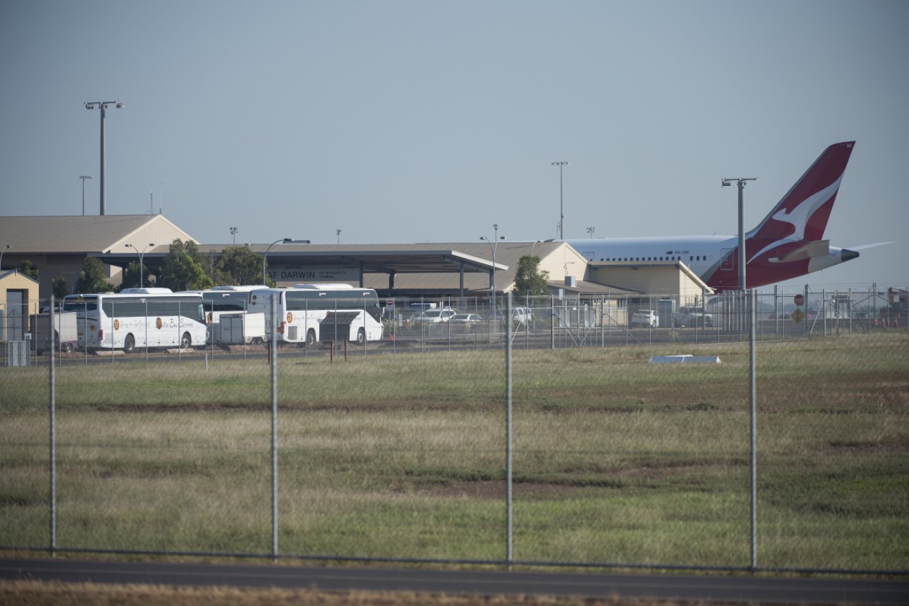 Buses stand by at Darwin airport to transport people to Howard Springs quarantine facilities.