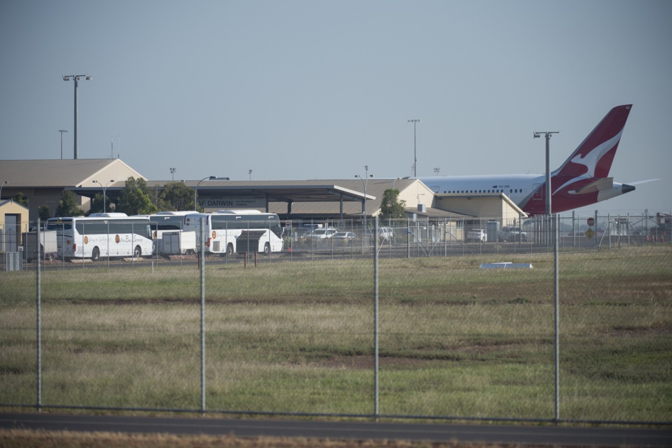 Buses stand by at Darwin airport to transport people to Howard Springs quarantine facilities. 