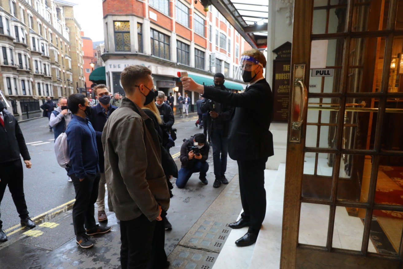 Theater-goers get their temparature checked as they arrive at St Martins theatre in London as UK eases virus restrictions allowing indoor locations such as pubs, museums, galleries to reopen.