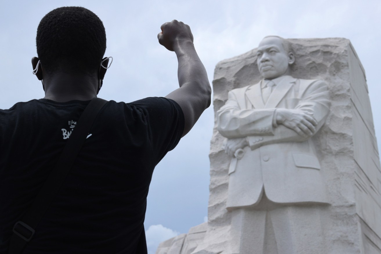 A man kneels and waves his fist at the Martin Luther King Jr memorial in Washington.