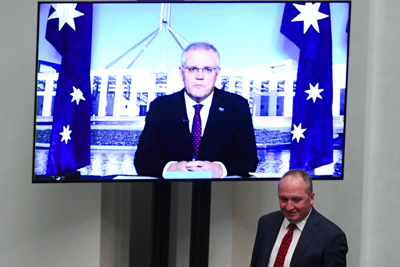 Barnaby Joyce walks past Scott Morrison, on video screen, in question time on Monday.