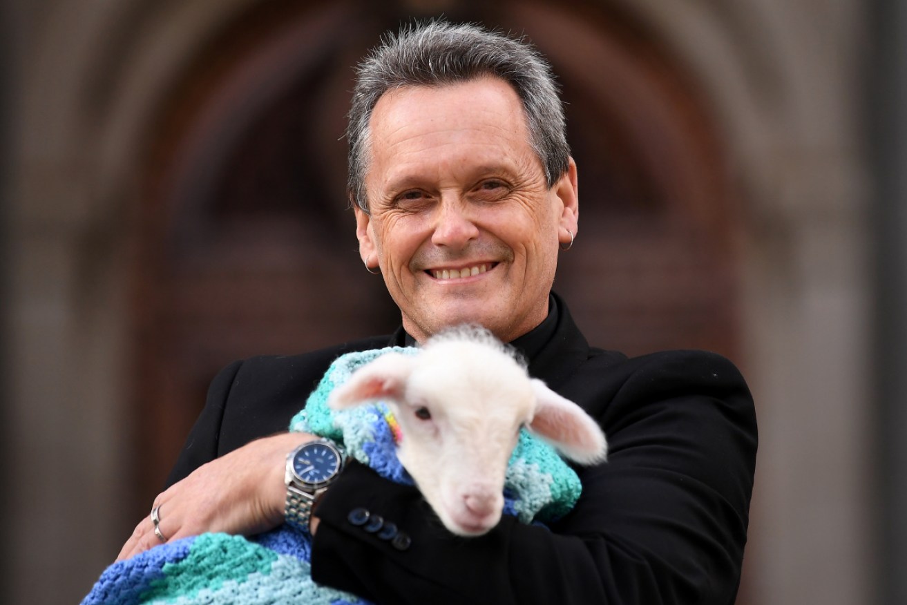 Animal Justice Party MP Andy Meddick with a warmly wrapped Lily the lamb in Melbourne on Wednesday.