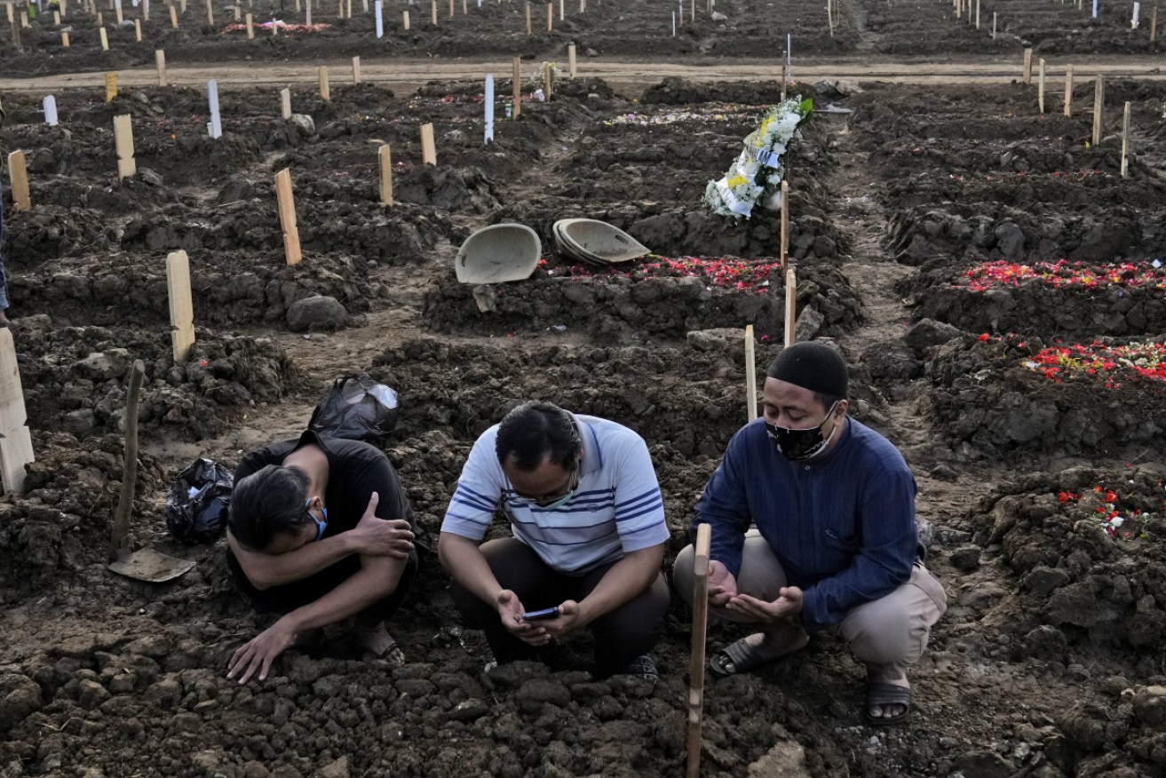 Men pray during the burial of a relative at Rorotan Cemetery which is reserved for those who died of COVID-19, in Jakarta, Indonesia.