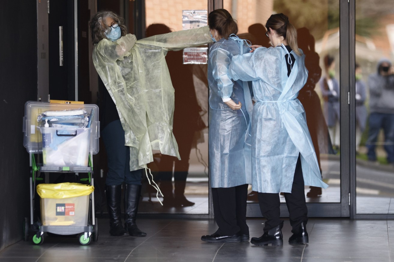 Health workers outside the Ariele apartment building in Melbourne where residents are locked down after a Covid positive Sydney-based removalist team visited the site.