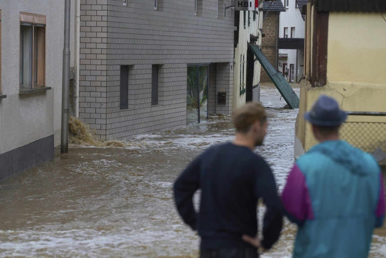 Two men look at a flooded street in Esch, Germany. More than 30 people are missing after torrential rain in the area.