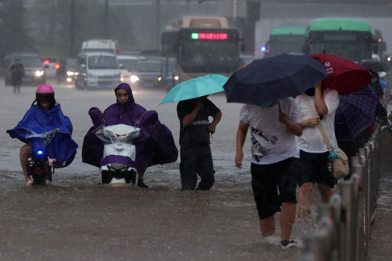 People wade through flood waters on a street after heavy rain in Zhengzhou.