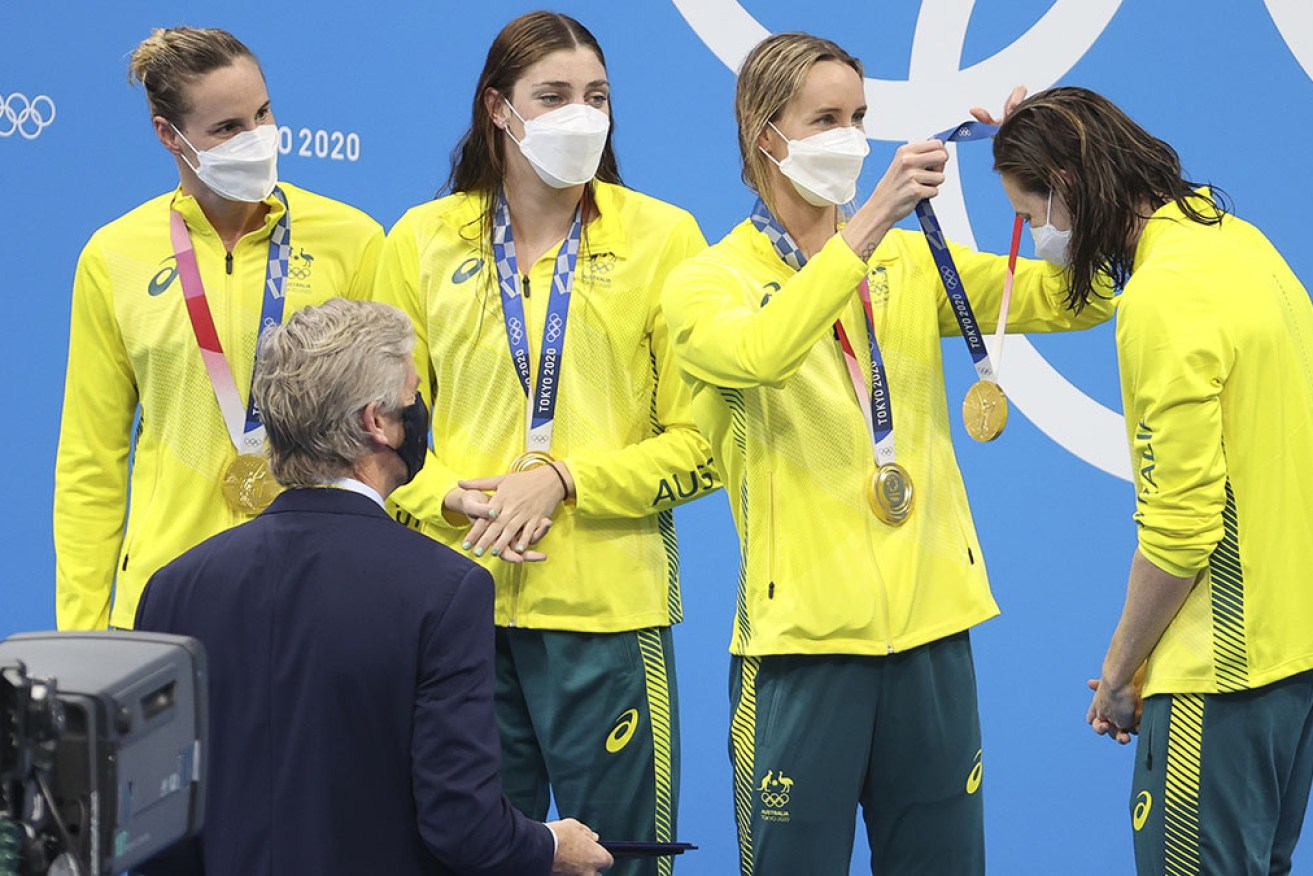 Bronte Campbell and Meg Harris watch Emma McKeon present Cate Campbell's 4x100m relay gold. 