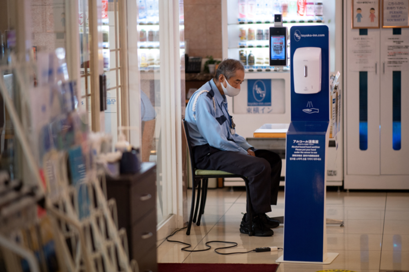 A sleepy security guard and a hand-sanitising station enforce the Olympics' anti-COVID measures.